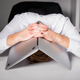 A man in a white collar shirt with a laptop tented over his head.
